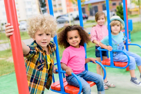Multicultural Group Little Children Riding Swings Playground — стоковое фото